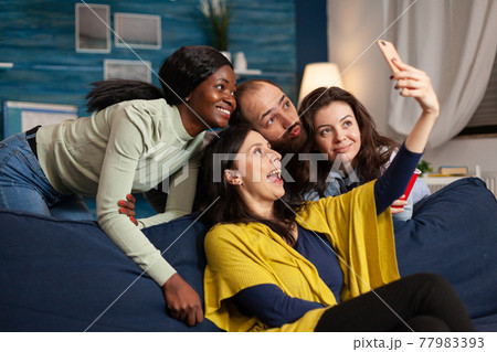 Multiethnic friends making funny faces while partying in apartment 77983393