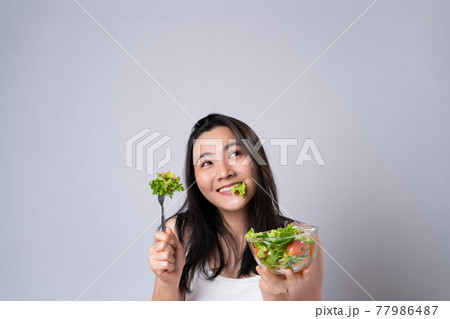 Asian woman eating salad isolated over white background. 77986487