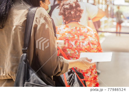 Passengers hand holding boarding pass queueing for departure. 77986524