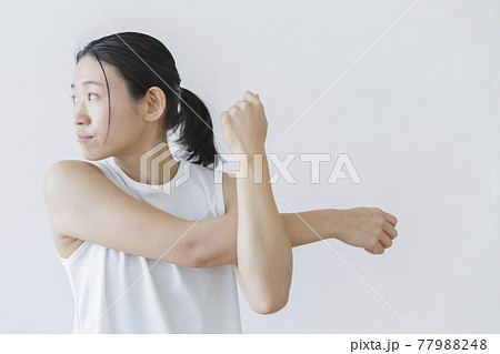 白い壁を背にストレッチをする女性 フィットネス 美容 77988248