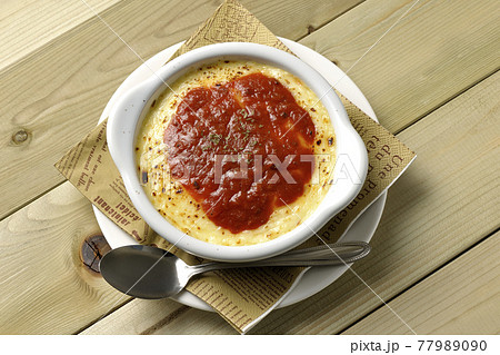 ペーパーナプキンと溶けて焦げ目がついたたっぷりチーズのドリア、グラタンとシルバースプーンを俯瞰で撮影 77989090