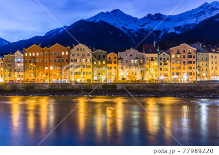 Panorama view of colorful buildings and mountains across from the flowing river of Innsbruck, Austria on a late evening night Panorama view of colorful buildings and mountains across from the flowing river of Innsbruck, Austria on a late evening night 77989220