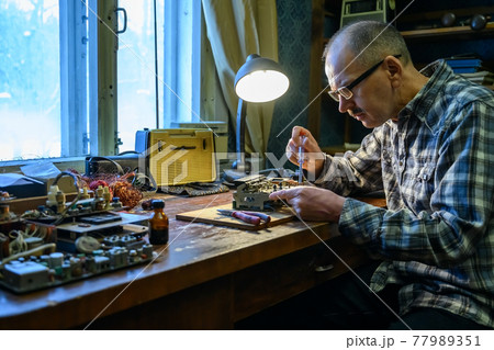 Male amateur radio operator repairing an old radio receiver Male amateur radio operator repairing an old radio receiver 77989351