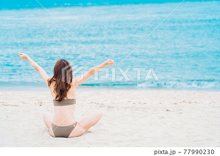 砂浜に座る水着姿の女性 77990230