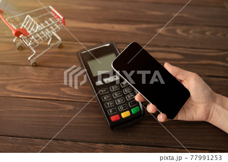 Female client holding smartphone with blank screen, paying for order using modern easy nfc technology Female client holding smartphone with blank screen, paying for order using modern easy nfc technology 77991253