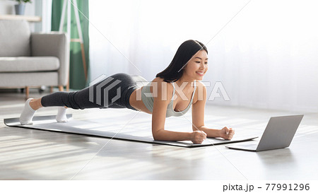 Fit Asian Woman Training At Home With Laptop, Making Plank Exercise Fit Asian Woman Training At Home With Laptop, Making Plank Exercise 77991296