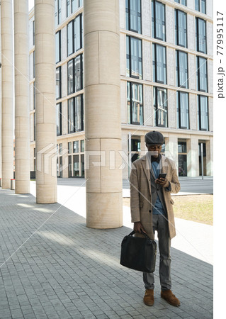 Businessman using phone outdoors Businessman using phone outdoors 77995117