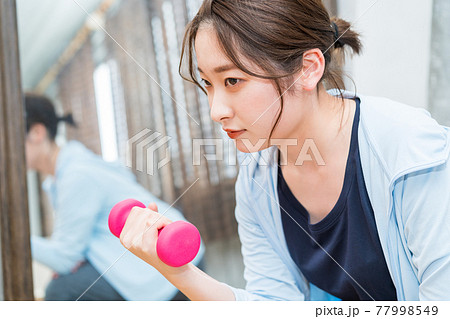 鏡の前でダンベルを使用してトレーニングする女性 77998549