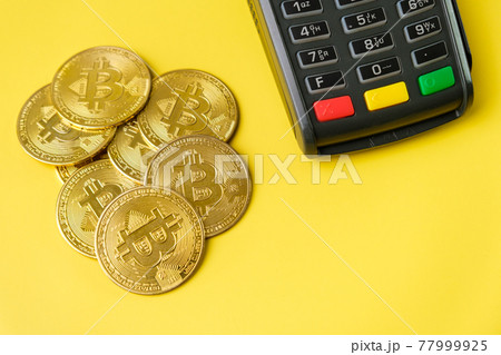 Bitcoin coins near POS payment terminal on the yellow background. Crypto currency for payment Bitcoin coins near POS payment terminal on the yellow background. Crypto currency for payment 77999925