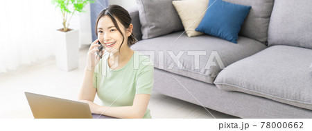 自宅でテレワークをしながらスマホで電話する女性 78000662