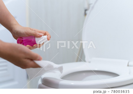 close up hand cleaning Toilet seat by a wet wipe with alcohol spray in public restroom for coronavirus prevention and hygiene before using 78003635