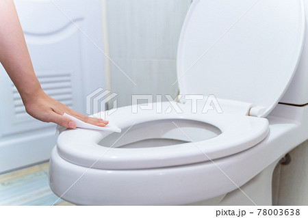 close up hand cleaning Toilet seat by a wet wipe with alcohol spray in public restroom for coronavirus prevention and hygiene before using close up hand cleaning Toilet seat by a wet wipe with alcohol spray in public restroom for coronavirus prevention and hygiene before using 78003638