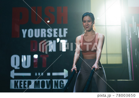 Asian athlete female exercising by using battle rope intense workout enjoying healthy bodybuilding endurance practice 78003650