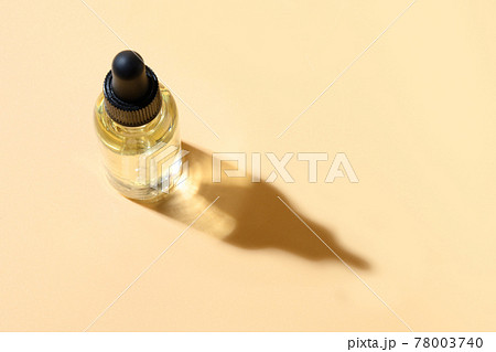 Cosmetics primer oil or essence in glass bottle on beige background. Cosmetics primer oil or essence in glass bottle on beige background. 78003740
