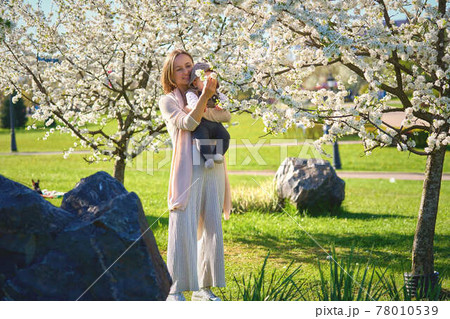 Woman with a child in a flowery garden. Family in spring garden 78010539