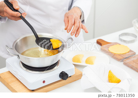 Senior woman frying a traditional dish from el Valle del Cauca in Colombia called empanada 78011350