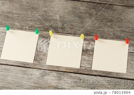 Square stickers pinned in a row on a wooden table. 78013904