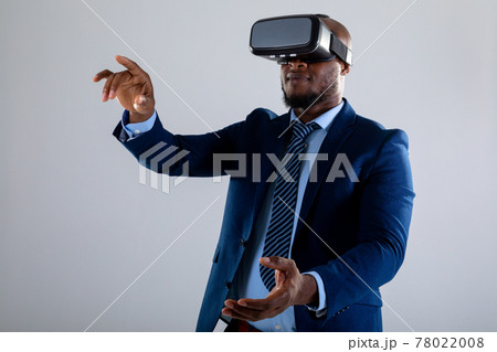 African american businessman wearing vr headset gesturing against grey background 78022008