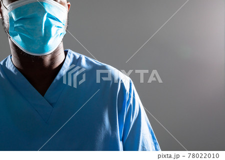 Mid section of african american male health worker wearing face mask against grey background 78022010