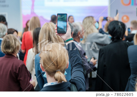 Woman recording video on smartphone in conference hall Woman recording video on smartphone in conference hall 78022605