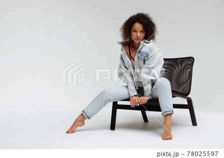 Stylish curly haired woman in denim outfit Stylish curly haired woman in denim outfit 78025597