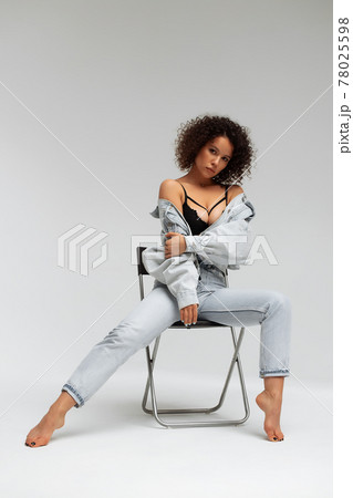 Stylish curly haired woman in denim outfit 78025598