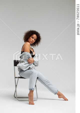 Stylish curly haired woman in denim outfit Stylish curly haired woman in denim outfit 78025611