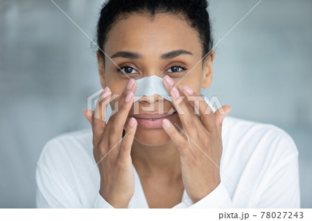 Portrait of positive beautiful Black woman during skincare cleansing procedures 78027243