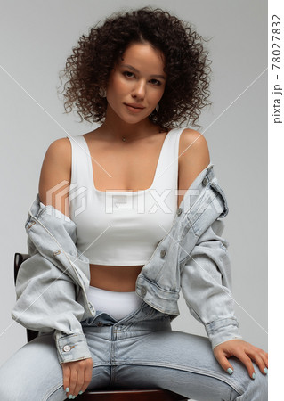 Stylish curly haired woman in denim outfit Stylish curly haired woman in denim outfit 78027832