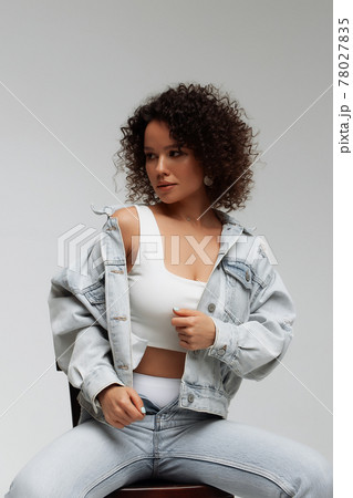 Stylish curly haired woman in denim outfit Stylish curly haired woman in denim outfit 78027835