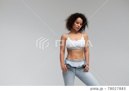 Stylish curly haired woman in denim outfit Stylish curly haired woman in denim outfit 78027883