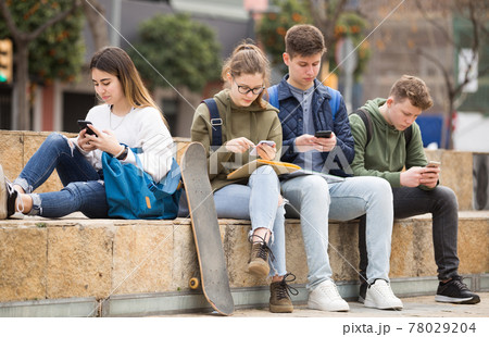 Teenagers are playing on smartphone on street 78029204