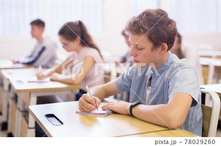 Focused teenage student writing lectures in classroom Focused teenage student writing lectures in classroom 78029260