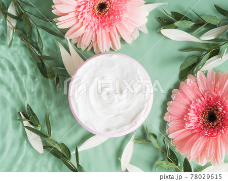 Skin care flat lay with generic cream jar with pink gerbera in water on green background Skin care flat lay with generic cream jar with pink gerbera in water on green background 78029615