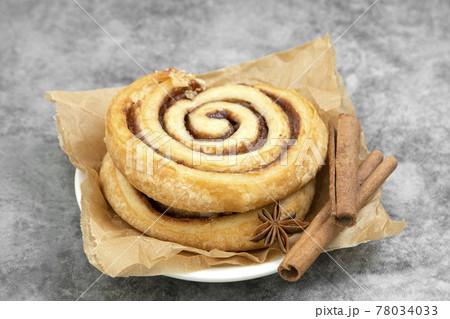 Cinnamon roll with cinnamon sticks over wooden table, danish pastry, sweet pastry for breakfast or snack. Cinnamon roll with cinnamon sticks over wooden table, danish pastry, sweet pastry for breakfast or snack. 78034033