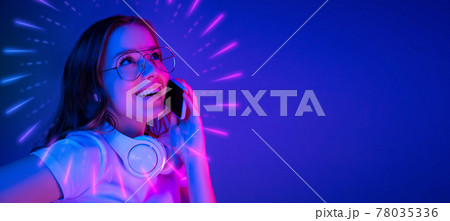 Close-up Caucasian woman's portrait isolated on blue studio background in multicolored neon light with luminescent rays 78035336