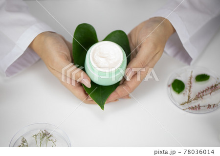 Hands hold jar with cream on green leaf, lab background with herbal ingredients Hands hold jar with cream on green leaf, lab background with herbal ingredients 78036014