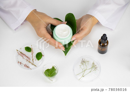 Cream jar in hands on white laboratory background, plan-based cosmetics 78036016