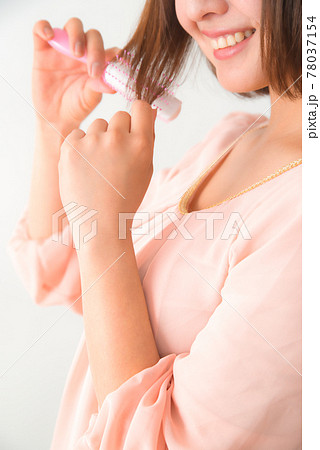 髪の毛先をブラシで梳かす若い女性 78037154
