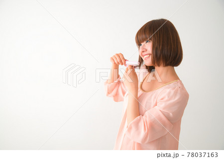 髪の毛先をブラシで梳かす若い女性 78037163