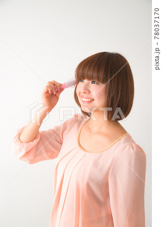 髪の毛先をブラシで梳かす若い女性 78037170