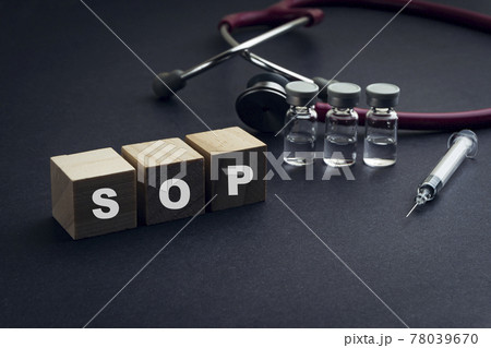 SOP text or Standard Operating Procedure on wooden cube with stethescope and syringe on black background 78039670