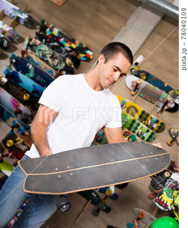 Nice young man choosing skateboard 78040109