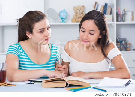 Teens girls doing homework and discussing Teens girls doing homework and discussing 78040372