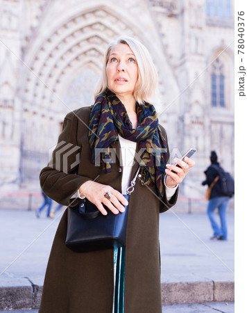 Smiling mature female is walking and talking by phone Smiling mature female is walking and talking by phone 78040376