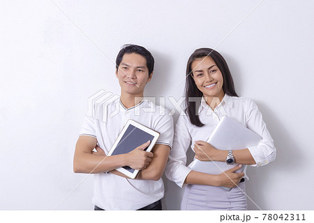 An Asian business woman standing in a modern collaborative office, smiling, looking at the screen of a tablet device, preparing a presentation about electronic devices. Cutting edge technology, 78042311