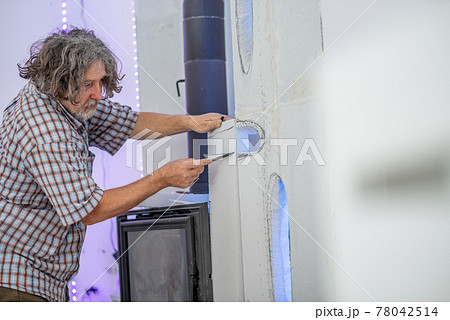 Senior man making ornamental forms around a fireplace Senior man making ornamental forms around a fireplace 78042514