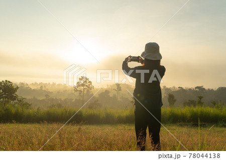 A backpacker tourist woman taking photos by phone, traveling at savannah mountain with fog mist at Thung Salaeng Luang National Park, Thailand. Nature landscape. People lifestyle adventure. Relax A backpacker tourist woman taking photos by phone, traveling at savannah mountain with fog mist at Thung Salaeng Luang National Park, Thailand. Nature landscape. People lifestyle adventure. Relax 78044138