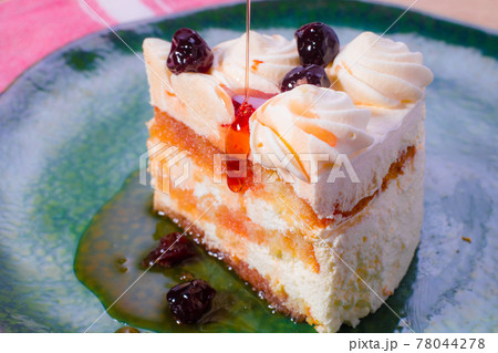 Slice of sponge cake with white cream and red cherry syrup. 78044278