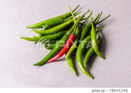 Slide of green chili peppers with one red on a light background. Slide of green chili peppers with one red on a light background. 78045248